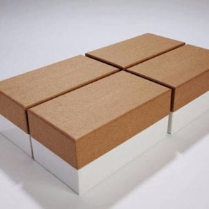 May include: Four brown cardboard boxes with white bases stacked in a staggered pattern. The boxes are empty and have a rough texture.