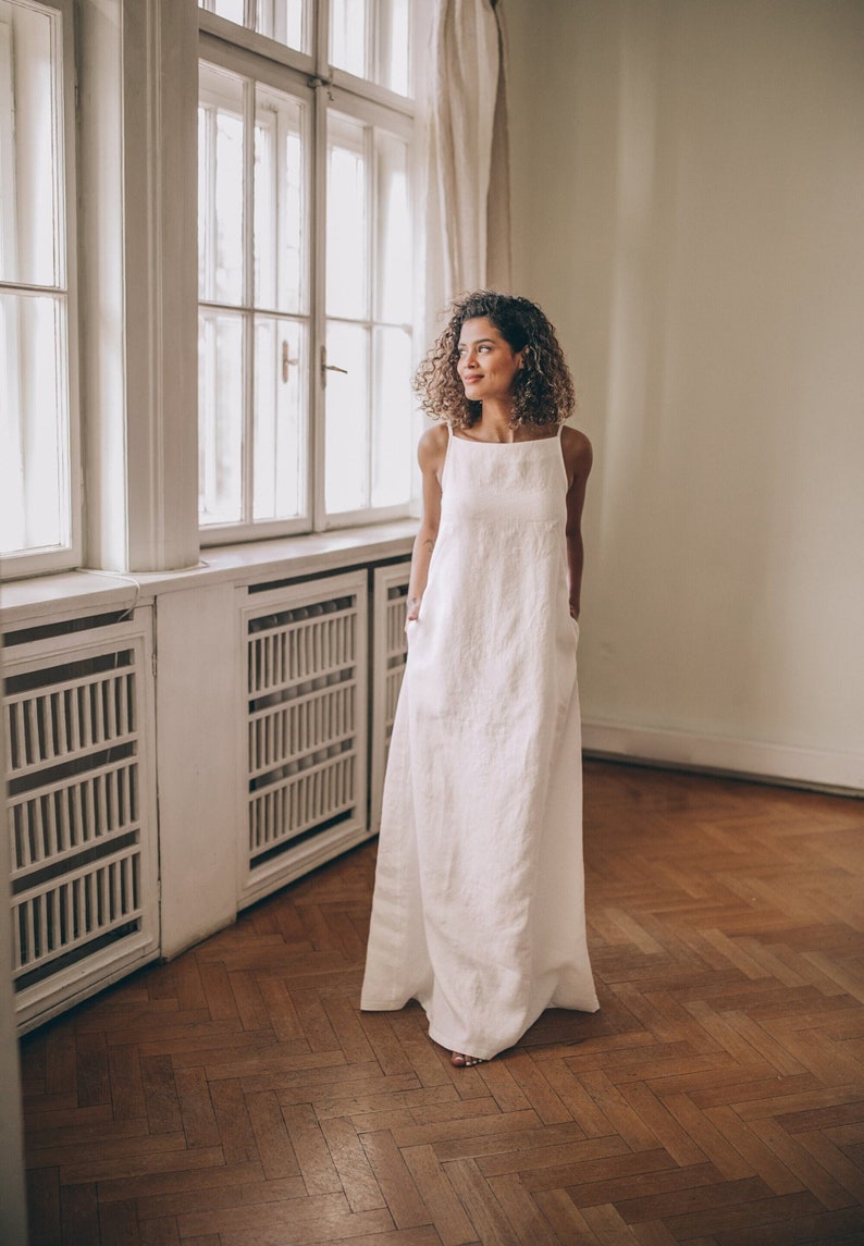 Designed entirely in natural linen, this floor length sleeveless dress is a seasonal essential. А minimalist piece that has elongated silhouette, hem pockets, boat neckline and a tie knot closure at the back.