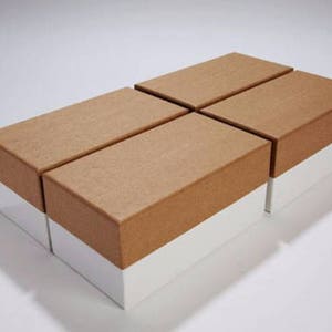 Puede incluir: Cuatro cajas de cartón marrón con fondos blancos apiladas en forma de escalonada. Las cajas están vacías y tienen una superficie texturizada.