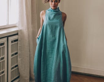 Vestido largo de lino, sin mangas, azul verdoso, con bolsillos, estilo burbuja y cuello alto.