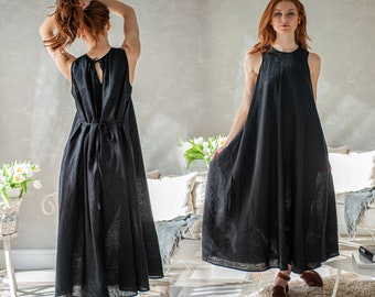 May include: A black sleeveless maxi dress with a round neckline and a flowing skirt. The dress features a keyhole back and a tie at the waist. The model is wearing brown leather sandals. The dress is made of a lightweight fabric.