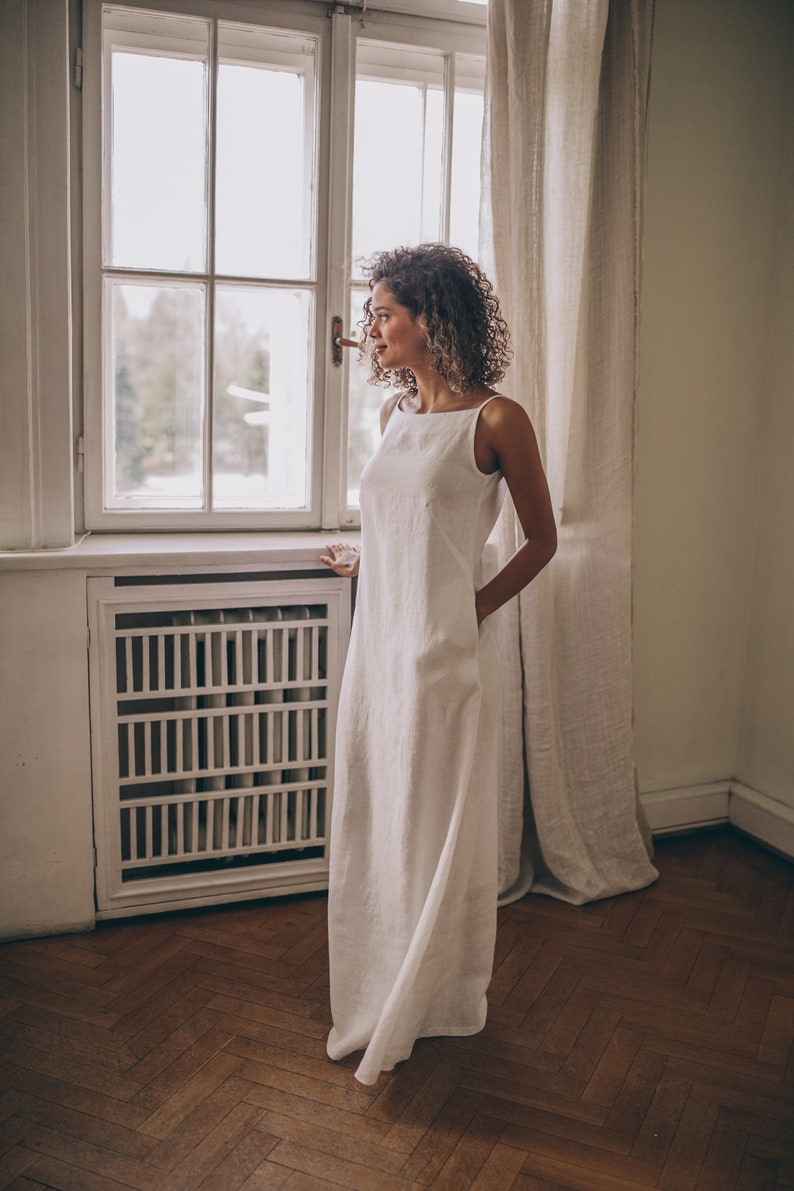 Designed entirely in natural linen, this floor length sleeveless dress is a seasonal essential. А minimalist piece that has elongated silhouette, hem pockets, boat neckline and a tie knot closure at the back.