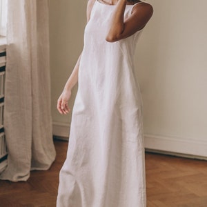 Designed entirely in natural linen, this floor length sleeveless dress is a seasonal essential. А minimalist piece that has elongated silhouette, hem pockets, boat neckline and a tie knot closure at the back.