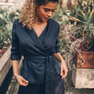 Puede incluir: Una blusa de lino azul marino con manga larga y un lazo en la cintura.