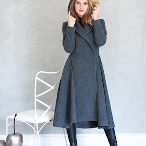 Woman wearing a gorgeous, warm and originally designed, this merino wool coat will be your darling for the chilly days. Featuring an oversize hood and side pockets, this jacket hugs the body at all the right parts and makes you look fabulous. A beautiful and cozy piece that will surely become a staple in your wardrobe for years to come.