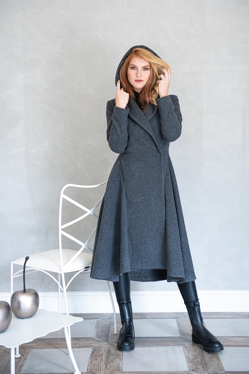 Woman wearing a gorgeous, warm and originally designed, this merino wool coat will be your darling for the chilly days. Featuring an oversize hood and side pockets, this jacket hugs the body at all the right parts and makes you look fabulous. A beautiful and cozy piece that will surely become a staple in your wardrobe for years to come.
