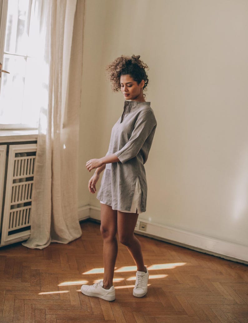 Sense the summer ease in this essential linen tunic top. It features a kaftan cut, a split shirt neckline, three-quarter sleeves and side slits.