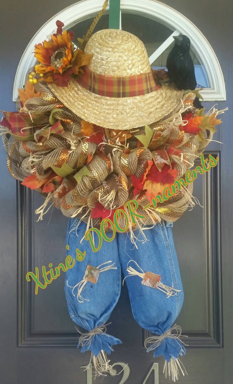 Puede incluir: Una corona de puerta artesanal con tem&aacute;tica de espantap&aacute;jaros. Presenta un sombrero de paja con una banda a cuadros, un cuervo negro y un peto vaquero. La corona est&aacute; adornada con follaje oto&ntilde;al, cintas y el texto "Xtine's DOOR ornaments".
