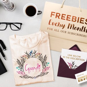 May include: A beige t-shirt with a floral wreath design and the text "Gpando Shop" in a circle. A brown paper bag with the text "FREEBIES Every Month FOR ALL OUR SUBSCRIBERS". A burgundy envelope with a white card inside that says "LINK BELOW IN THE DESCRIPTION". A business card with the text "FOLLOW ME @CPANDO SHOP" and social media icons.