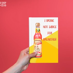 Puede incluir: Una libreta amarilla y blanca con el texto "I drink hot sauce for breakfast" y una ilustraci&oacute;n de acuarela de una botella de salsa picante roja con un chile verde en la etiqueta.