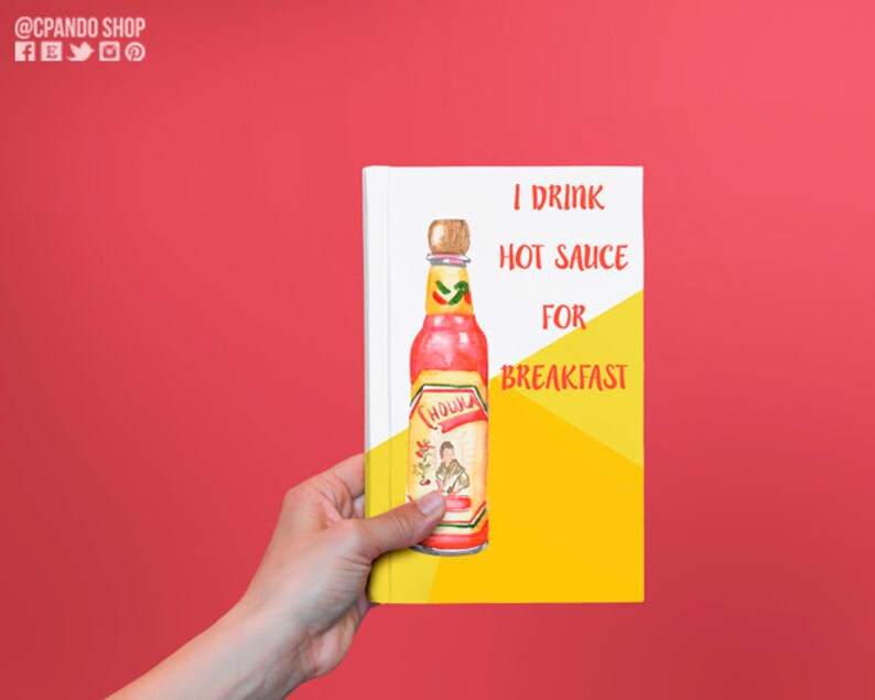 Puede incluir: Una libreta amarilla y blanca con el texto "I drink hot sauce for breakfast" y una ilustraci&oacute;n de acuarela de una botella de salsa picante roja con un chile verde en la etiqueta.