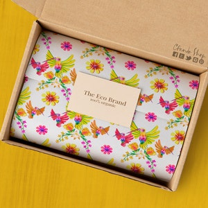 May include: A cardboard box with a white tissue paper lining. The tissue paper has a colorful pattern of hummingbirds and flowers. A small card with the text "The Eco Brand 100% organic" is visible on the tissue paper.