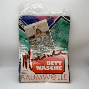 Könnte beinhalten: Ein verpacktes Bettwäsche-Set mit einem farbenfrohen abstrakten Design in Grün, Blau, Rosa und Schwarz. Die Verpackung enthält ein Foto der Bettwäsche und ein Etikett mit deutschem Text.