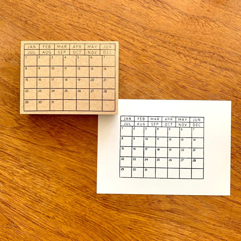 May include: Two brown wooden calendar stamps with black ink. The top stamp shows the months January through June and July through December. The bottom stamp shows the months January through June and July through December.
