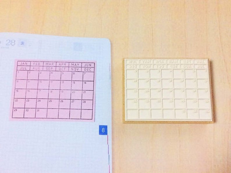 May include: Two calendar stamps, one pink and one white, with the months of the year printed on them. The pink stamp has the numbers 1 through 31 printed in the squares. The white stamp has blank squares.