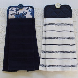 May include: Two kitchen towels with blue and white stripes. The towels have a blue quilted fabric pocket with a button on the top.