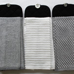 May include: Three kitchen towels with black quilted fabric backing and button closures. The towels are gray, white, and gray with a checkered pattern.
