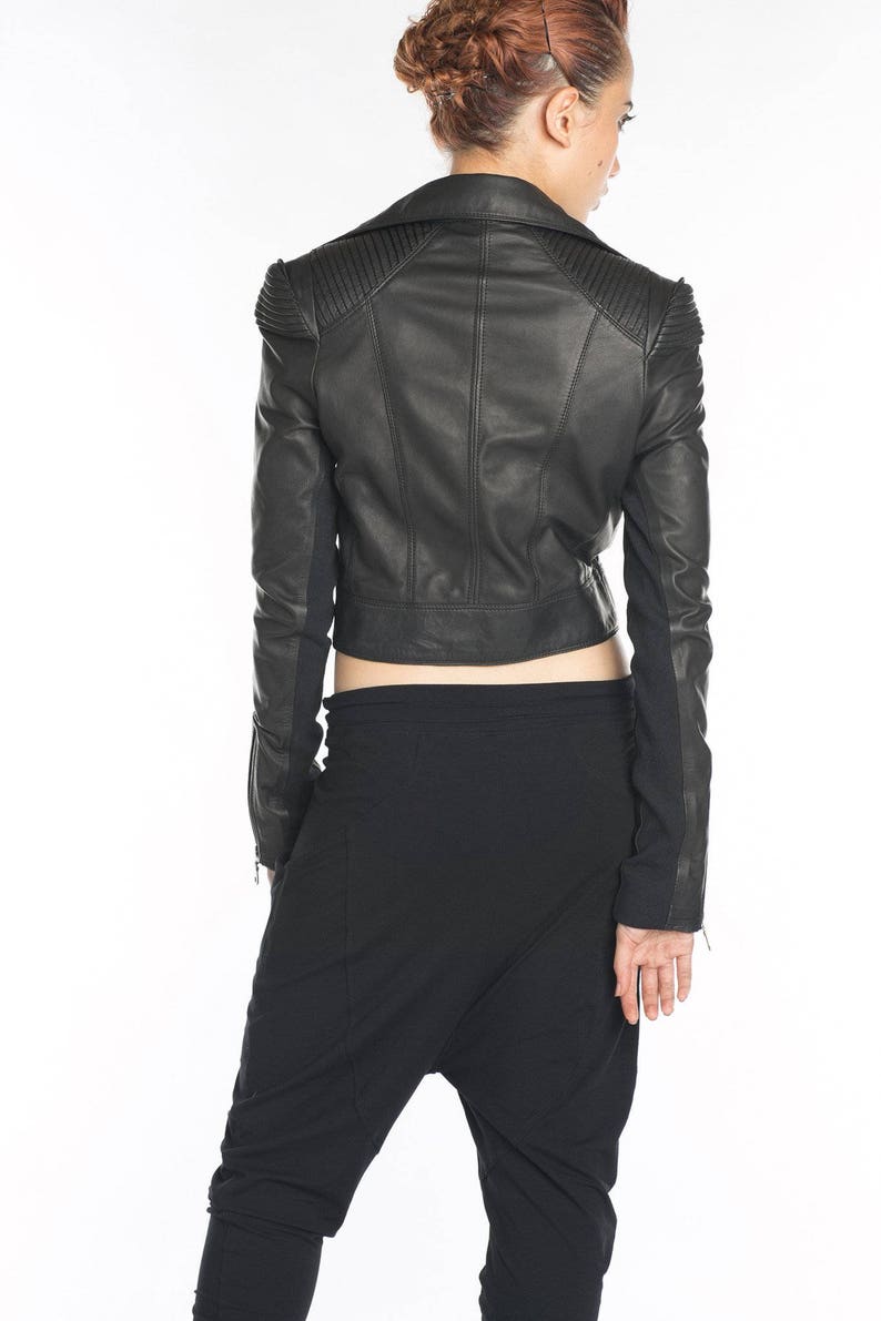 May include: A black leather jacket with a cropped cut and a zipper closure. The jacket has a stand-up collar and long sleeves.