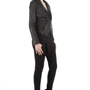 Puede incluir: Chaqueta de cuero negra con cremallera asim&eacute;trica y cuello drapeado. La chaqueta se combina con pantalones negros y botines con cu&ntilde;a negros. El conjunto es de estilo moderno y atrevido.