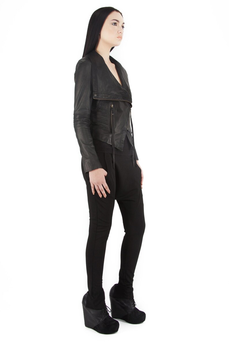 Puede incluir: Chaqueta de cuero negra con cremallera asim&eacute;trica y cuello drapeado. La chaqueta se combina con pantalones negros y botines con cu&ntilde;a negros. El conjunto es de estilo moderno y atrevido.