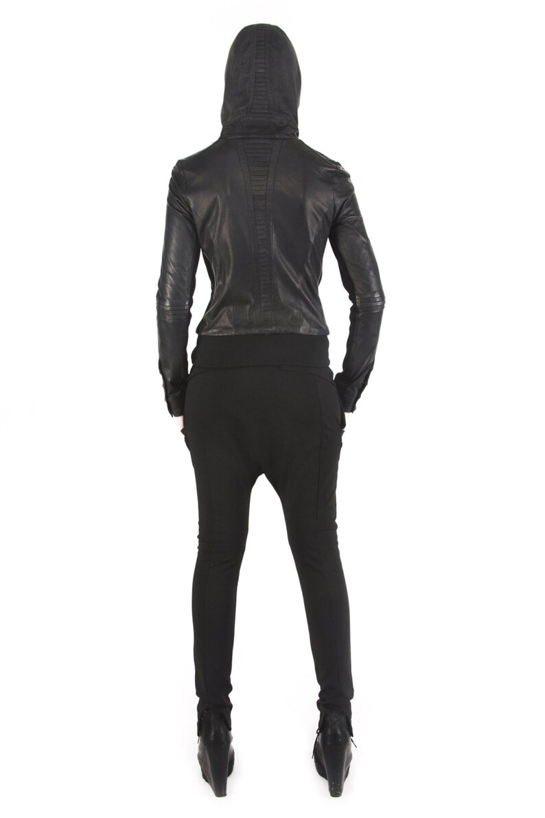 May include: A black leather jacket with a hood and zipper closure. The jacket has a quilted design on the back and is worn over black pants.