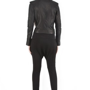 Puede incluir: Chaqueta de cuero negra con detalles en los hombros y un conjunto negro a juego. La chaqueta tiene un corte entallado y los pantalones tienen una silueta holgada &uacute;nica. El conjunto se completa con botines negros con cu&ntilde;a.