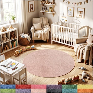 May include: A round, blush pink rug dominates a nursery scene. The rug is centered on a wooden floor, surrounded by a white crib, two armchairs, and a small white table with chairs. Wooden toy train and framed animal art complete the cozy, inviting space.