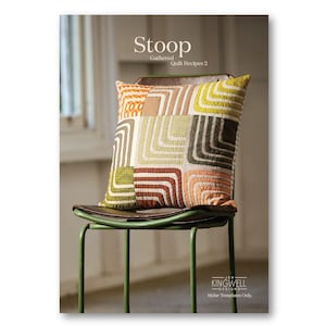 以下が含まれることがあります： 「Stoop - Gathered Quilt Recipes 2」の表紙には、オレンジ、緑、茶色、クリーム色の幾何学模様のパッチワーククッションが描かれています。茶色の革張りの座面がある緑色の椅子の上に置かれています。この本はJen Kingwell Designsによるものです。