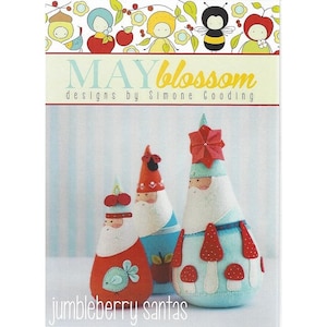 May include: A set of three felt Christmas ornaments, each shaped like a gnome. The gnomes are wearing red, blue, and white hats and have white beards. The ornaments are decorated with red and white polka dots and mushrooms. The text "jumbleberry santas" is printed below the ornaments.