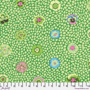 May include: A green fabric featuring a repeating pattern of small, irregular light green spots and various stylized flowers in shades of pink, blue, and light green. A white ruler at the bottom shows measurements up to 30 cm.