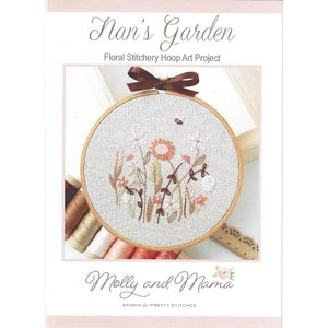 May include: A floral embroidery hoop art project titled "Nan's Garden" by Molly and Mama Studio for Pretty Stitches. The hoop features a white linen background with embroidered flowers in shades of pink, brown, and white.