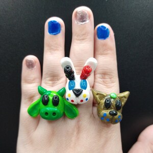 May include: Three colorful animal rings, a green cow, a white rabbit with red ears and a brown dog with blue spots.