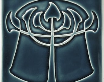 May include: A blue ceramic tile with a white design of a stylized tree with a central trunk and branches extending out to the sides. The tree is reminiscent of a menorah.