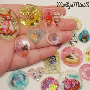May include: Assortment of colorful resin charms with various designs, including a deer, a heart, a hedgehog, a penguin, a pig, a cat, a butterfly, a flower, and a cartoon character. The charms are decorated with glitter and have a variety of shapes and sizes.