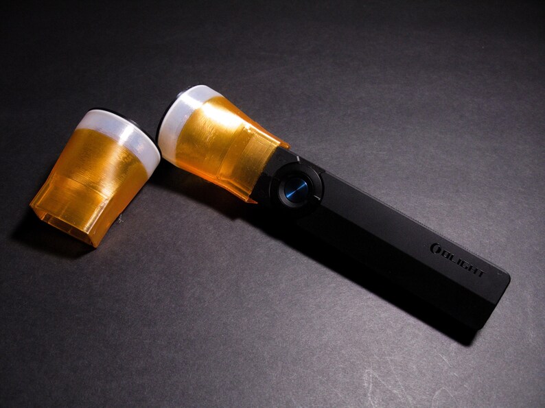 Pode incluir: Uma lanterna preta com cabe&ccedil;a dourada e bot&atilde;o azul. A lanterna tem um corpo retangular e uma tampa de cabe&ccedil;a dourada separada. O nome da marca &eacute; impresso na lateral.