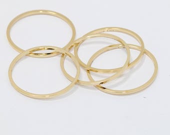 May include: Several gold-colored bangle bracelets are arranged on a white surface. The bracelets are thin, circular, and have a smooth, polished finish. The bangles are overlapping each other.