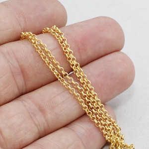 Könnte beinhalten: Nahaufnahme einer goldfarbenen Halskette mit mehreren Strängen. Die Kette besteht aus kleinen, kreisförmigen Gliedern, und das Gesamtdesign ist zart und elegant. Die Halskette wird vor einem neutralen Hintergrund präsentiert.