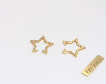 May include: Two gold-coloured star-shaped charms with a cut-out design, and a small rectangular tag that reads "Raw Brass". The charms are on a white background.