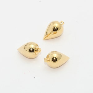 May include: Three gold-colored, teardrop-shaped pendants with a shiny, reflective surface. Each pendant has a small loop at the top for attaching to a chain or other jewelry component. The pendants are displayed on a white background.