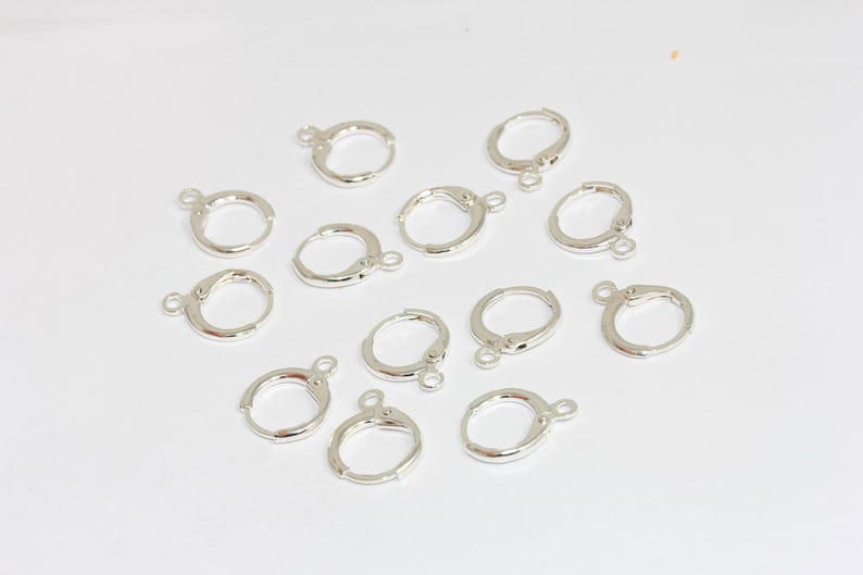 Peut inclure: Un ensemble de douze appr&ecirc;ts de boucles d'oreilles cr&eacute;oles en m&eacute;tal argent&eacute;, chacun dot&eacute; d'une petite boucle circulaire &agrave; la base pour suspendre des breloques ou des pendentifs. Ces composants de bijouterie pr&eacute;sentent un m&eacute;canisme de fermeture &agrave; charni&egrave;re.