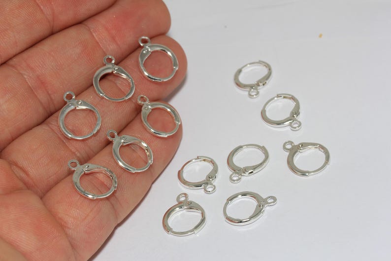 Peut inclure: Une collection de petits appr&ecirc;ts de boucles d'oreilles circulaires en m&eacute;tal argent&eacute; avec des fermoirs &agrave; levier articul&eacute;s. Chaque pi&egrave;ce pr&eacute;sente une petite boucle &agrave; la base pour attacher des breloques, avec une finition m&eacute;tallique polie.