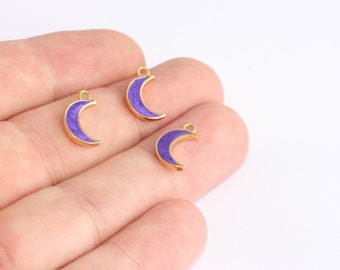 May include: Three gold-colored crescent moon charms with a purple enamel fill. Each charm has a small loop at the top for attaching to jewelry. The charms are displayed against a white background.
