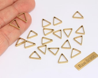 Puede incluir: Una colección de pequeños triángulos de latón de marco abierto dispersos sobre una superficie blanca. También hay un pequeño rectángulo de latón con el texto "Raw Brass". Estas formas geométricas son ideales para la fabricación de joyas o proyectos de artesanía.
