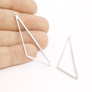 May include: Two silver-colored, open-frame triangle charms. Each charm has a small loop at the top for attaching to a chain or other jewelry component. The charms are displayed against a white background.