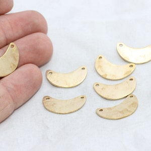 Puede incluir: Una colecci&oacute;n de componentes de joyer&iacute;a de lat&oacute;n en forma de media luna. Cada pieza tiene dos peque&ntilde;os agujeros para sujetar a otros elementos. Los componentes tienen una superficie ligeramente texturizada y un tono dorado c&aacute;lido. Est&aacute;n dispuestos sobre una superficie blanca.