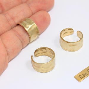May include: Close-up of three raw brass rings with a hammered texture. One ring is on a finger, and two are open-ended. A small brass rectangle with the text "Raw Brass" is also present.