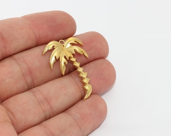 May include: A gold-colored palm tree charm with detailed fronds and a textured trunk. The charm has a small loop at the top for attaching to jewelry or other crafts. The design is a tropical theme.
