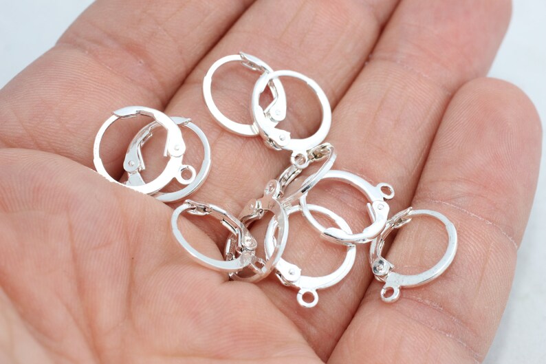 Peut inclure: Un ensemble de petites boucles d'oreilles cr&eacute;oles en m&eacute;tal argent&eacute; avec fermoirs &agrave; levier articul&eacute;s. Chaque anneau circulaire comporte une minuscule boucle &agrave; la base pour attacher des breloques, con&ccedil;ues pour la cr&eacute;ation de bijoux.