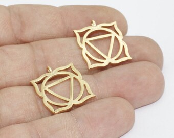 May include: Two gold-colored metal pendants. Each pendant features a stylized lotus flower design with a central triangle and circle. The pendants are small, with a loop at the top for attaching to a chain or other jewelry.