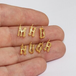 Puede incluir: Amuletos de alfabeto de metal dorado. Los amuletos tienen la forma de las letras M, H, B, H, O y A. Cada amuleto tiene un peque&ntilde;o lazo en la parte superior para sujetarlo a una cadena u otra joya. Las letras tienen un dise&ntilde;o de rayos de sol.